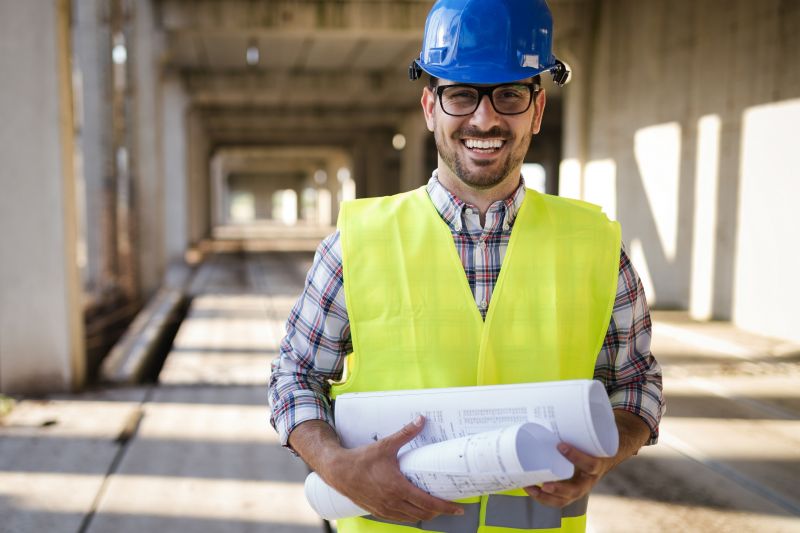 Bau und Handwerk, Handwerker auf der Baustelle hält Baupläne in den Händen